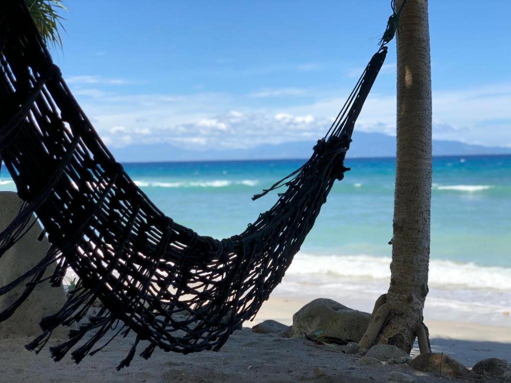 a hammock hanging from a palm tree on a beach at Pulau Weh Paradise in Sabong