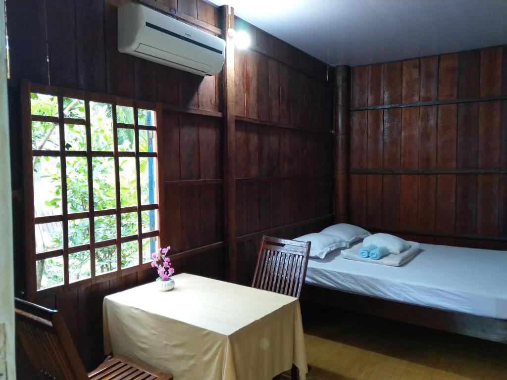 a room with two beds and a table and two windows at Nam Binh Homestay in Ben Tre