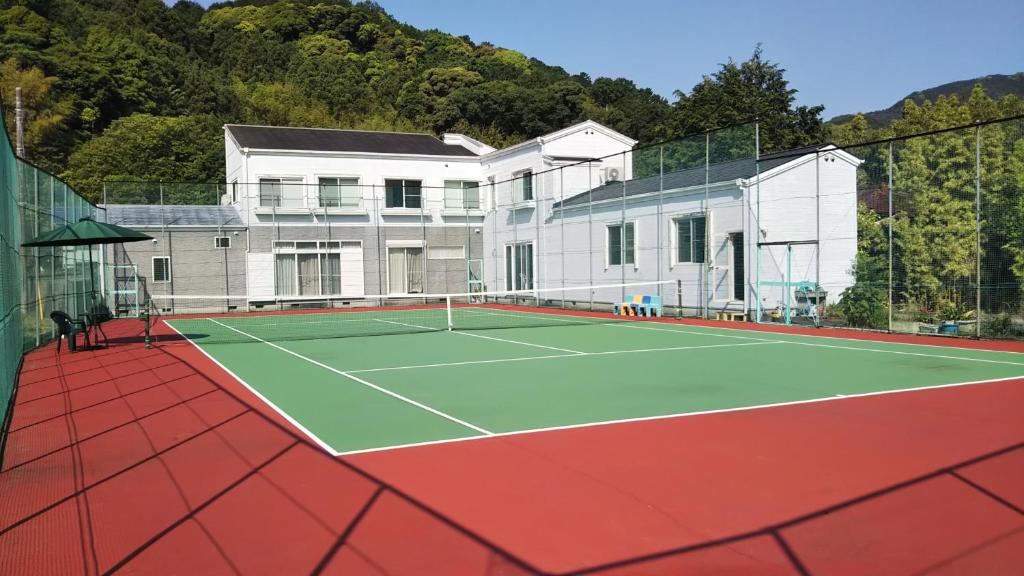 una pista de tenis frente a una casa en ペンション ラリー en Kawazu