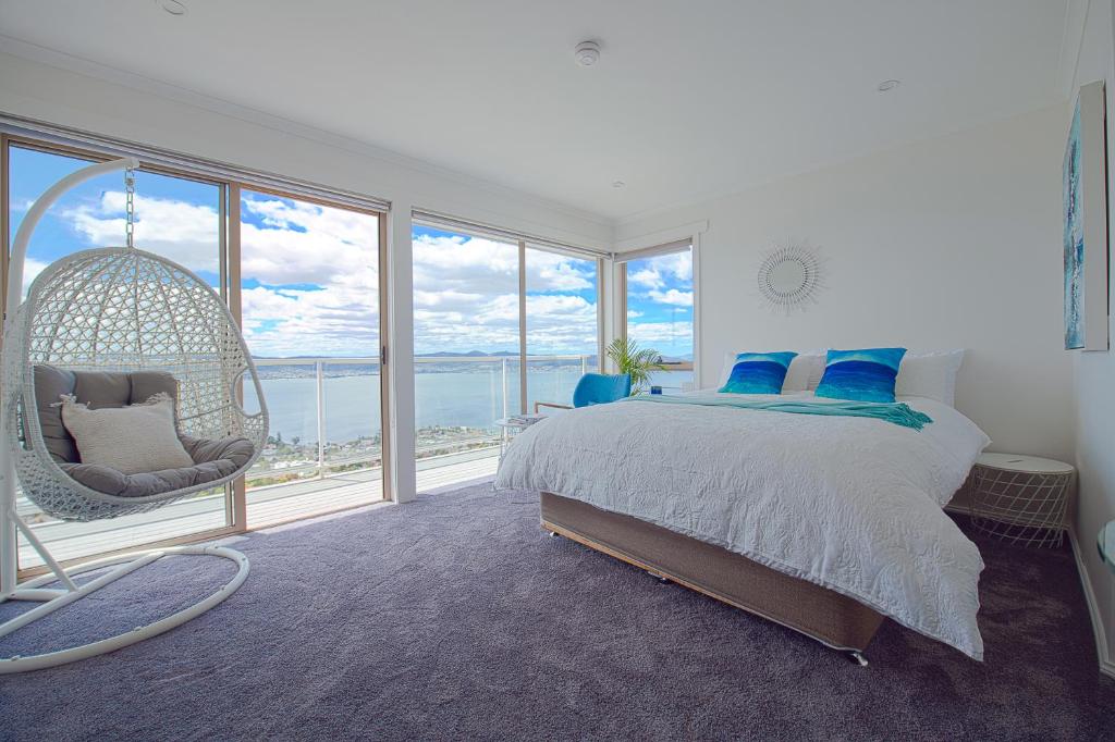 una camera da letto con letto a dondolo e ampia finestra di Nature & Relax House, Panoramic sea view, Free parking 37 a Hobart