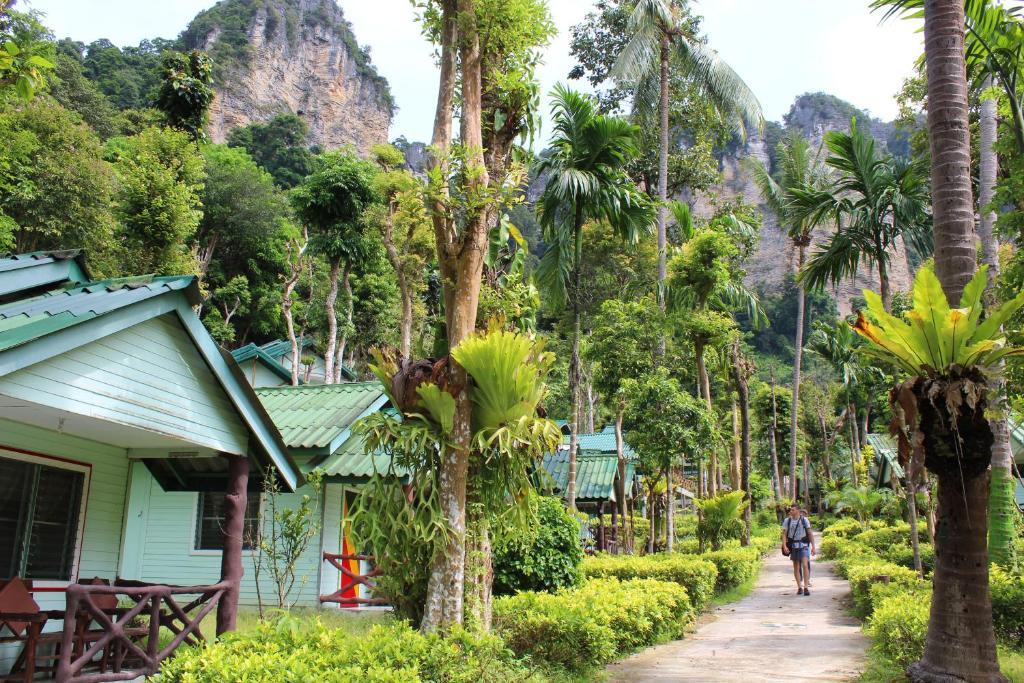 Een man loopt over een pad naast een huis met palmbomen. bij Chill Out Bar and Jungle Bungalows in Krabi town