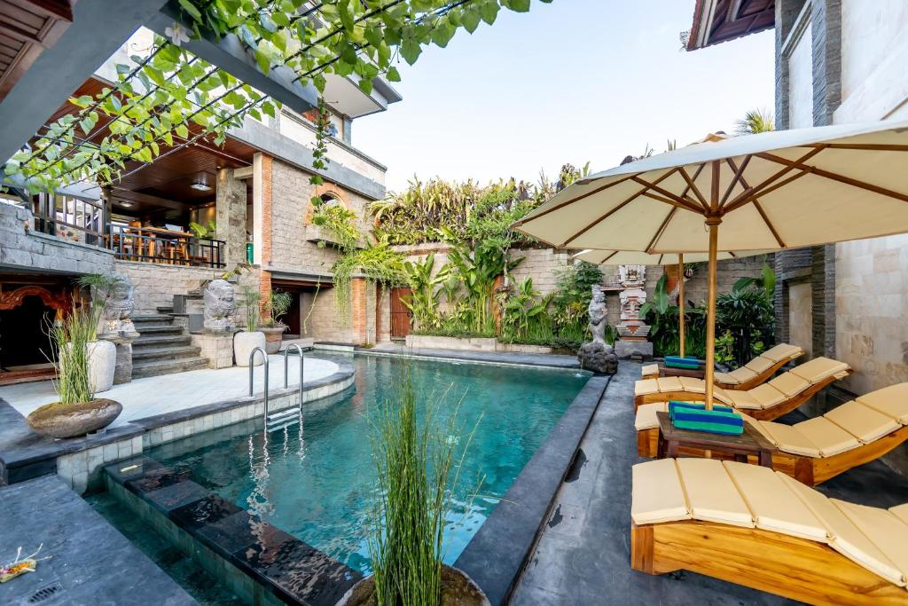 an indoor pool with chairs and an umbrella at Juwuk Manis in Ubud