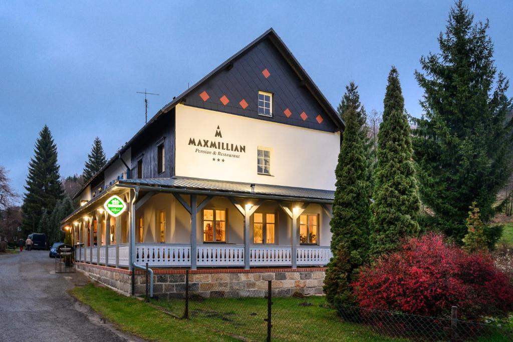 un gran edificio con un cartel en el costado en MAXMILLIAN Pension & Restaurant en Mařenice