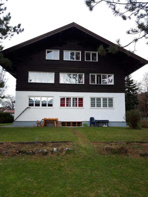 ein schwarzweißes Haus mit einem Picknicktisch davor in der Unterkunft Ferienwohnung Buddatsch-Hofmann in Oberstdorf
