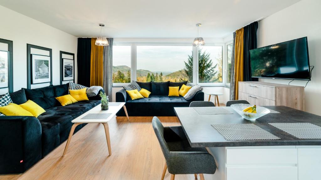 a living room with a black couch and yellow pillows at Apartamenty EverySky - Wyspiańskiego 4-4a in Karpacz