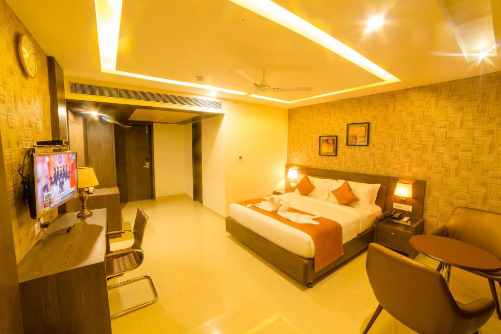 ein Hotelzimmer mit einem Bett und einem TV in der Unterkunft Hotel Indraprasttha in Vijayawāda
