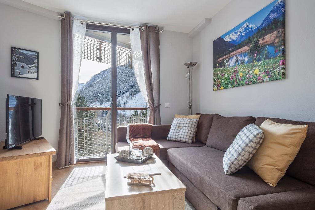 uma sala de estar com um sofá e uma grande janela em Acogedor Apartamento Baqueira 1500 em Baqueira-Beret