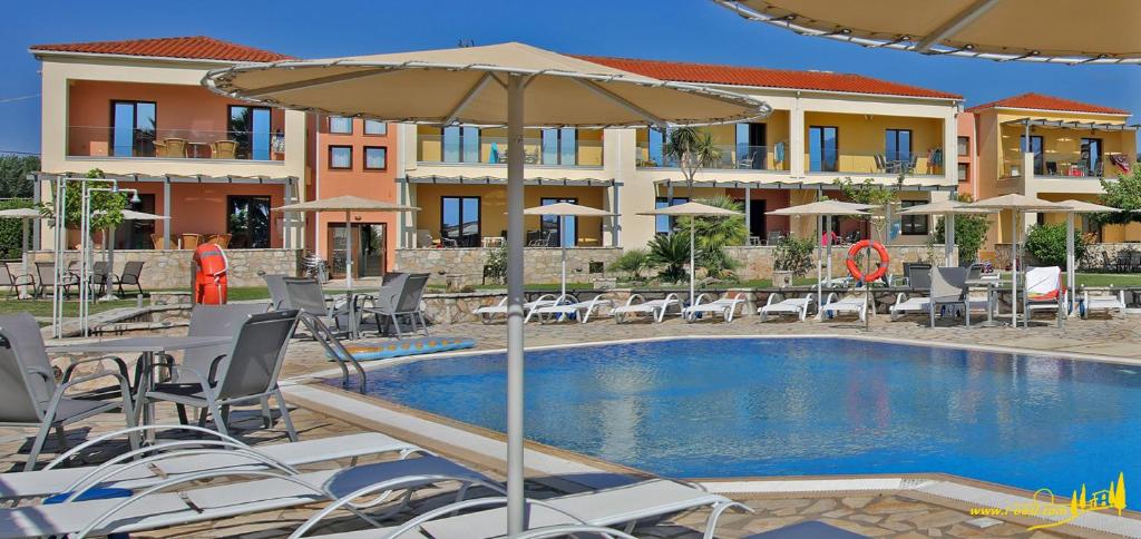 a swimming pool with chairs and an umbrella at Oasis by the Sea in Chiliadou