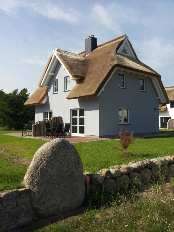 a house with a thatched roof and a large rock at Haus Backbord in Zirchow