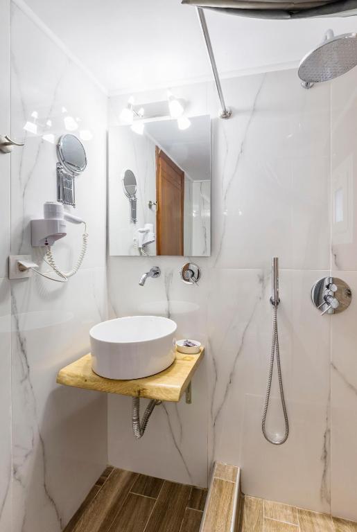 a white bathroom with a sink and a shower at Hotel Almira in Agia Triada
