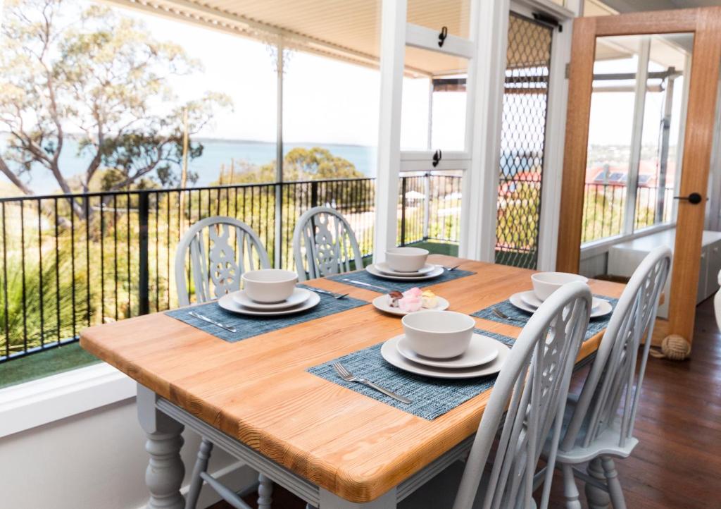 a dining room table and chairs with a view of the ocean at Estuary Cottage, Mandurah, Dawesville in Mandurah