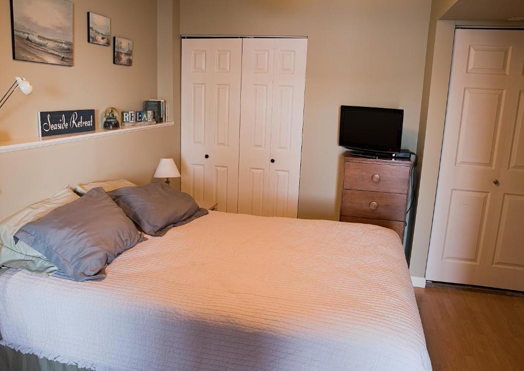 1 dormitorio con cama y vestidor con TV en Inlet Beach House B&B, en North Saanich