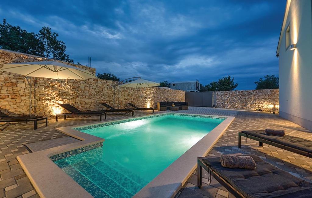 a swimming pool in front of a stone wall at Holiday Home Ivan in Peroj