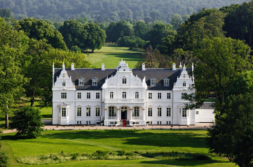 een groot wit huis op een weelderig groen veld bij Kokkedal Slot Copenhagen in Hørsholm