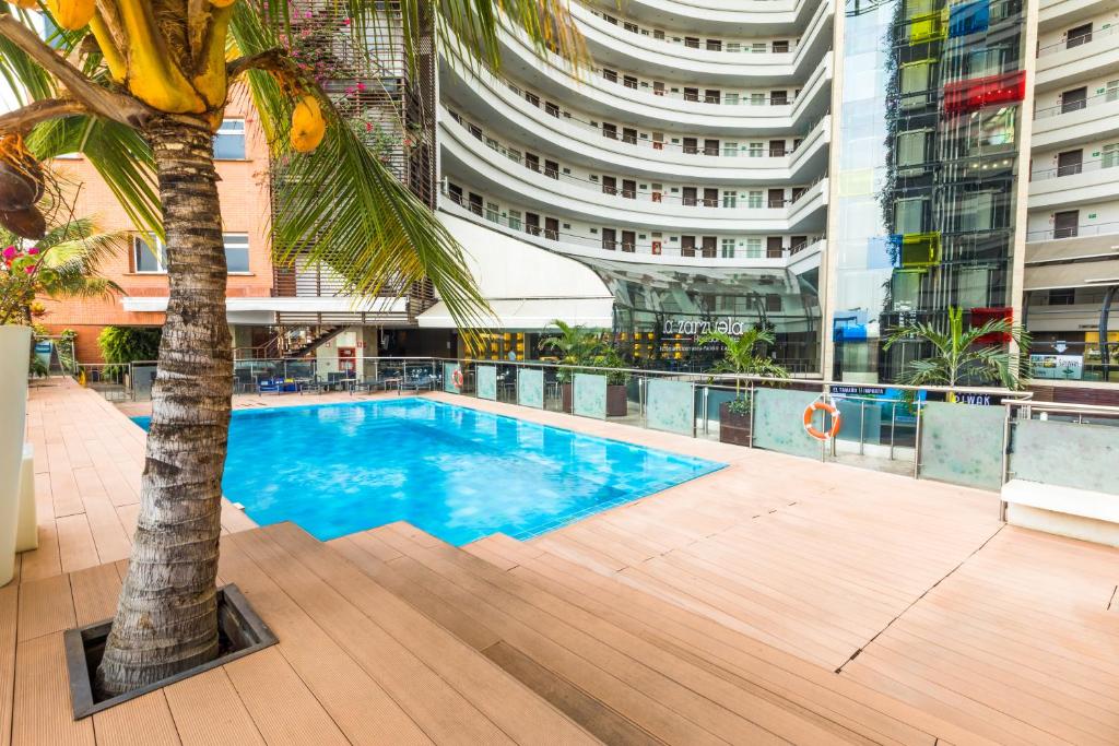 una piscina con una palmera en el medio de un edificio en Hotel Spiwak Chipichape Cali, en Cali