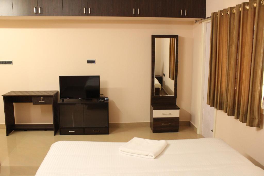 a bedroom with a bed and a tv and a mirror at Phoenix Serviced Apartment - Sri Illam in Chennai