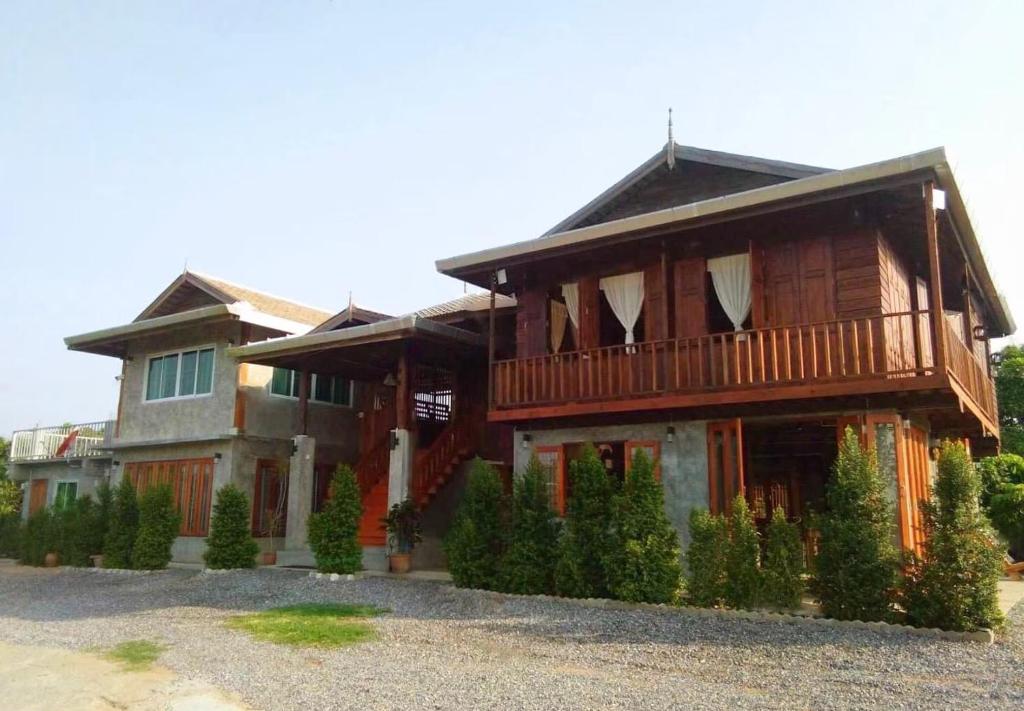 a large house with a balcony on top of it at เฮือนฮอมคำโฮมสเตย์(Huanhomkham homestay) in Chiang Mai