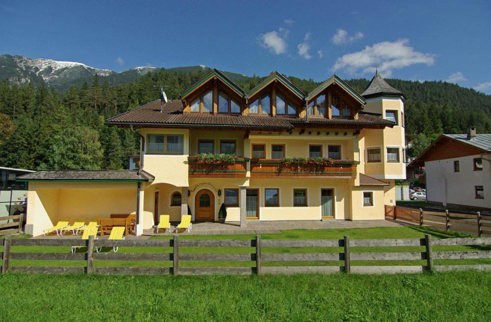 ein großes Haus mit einem Zaun davor in der Unterkunft Tonis Appartements am Achensee in Achenkirch