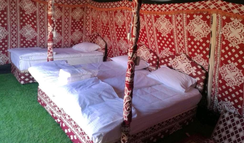2 camas en una habitación con papel pintado rojo y blanco en Crescent Desert Private Camp en Shāhiq