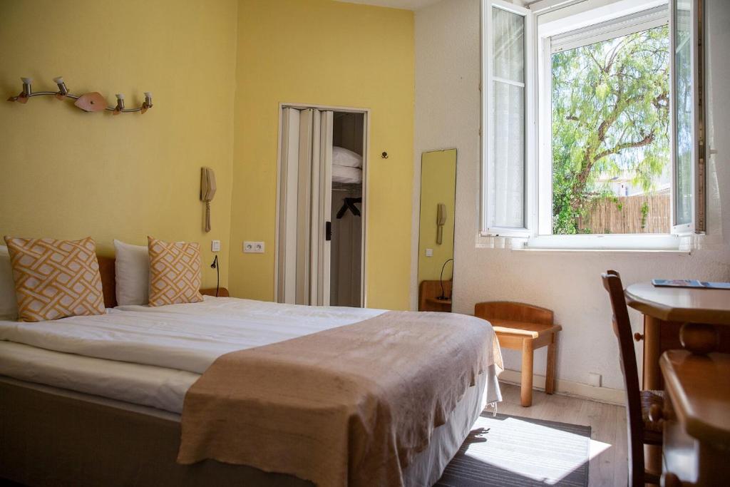 a bedroom with a bed and a window and a desk at Hôtel Du Soleil in Saint-Raphaël