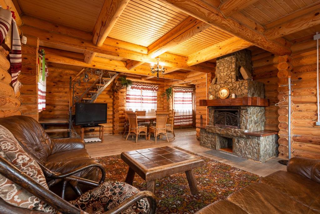 a living room with a fireplace in a log cabin at Gostynnyi Dvir Burkut in Verkhovyna