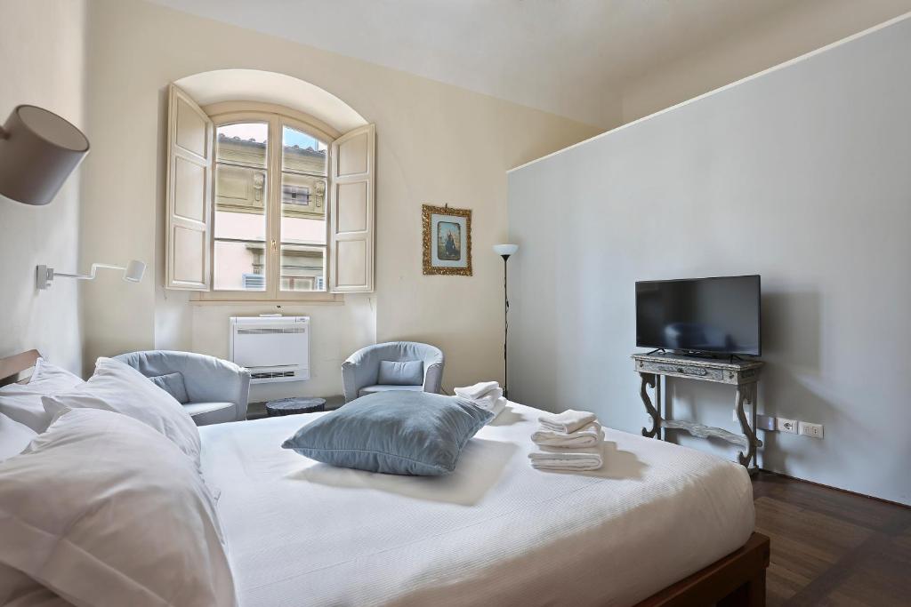 a bedroom with a bed with two chairs and a television at Apt. Fiordaliso - Pauline Suites, Palazzo Borghese in Florence