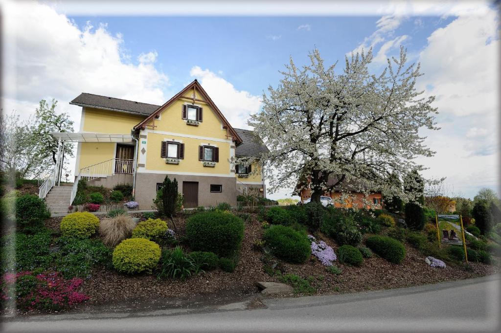 une maison jaune avec un arbre à fleurs dans une cour dans l'établissement Frühstückspension-Appartement Liebmann, à Schamberg