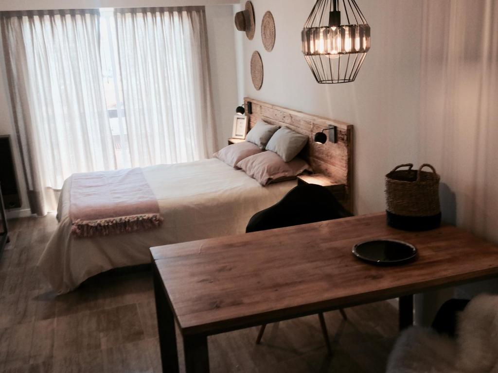 1 dormitorio con cama y mesa de madera en Varese Playa en Mar del Plata