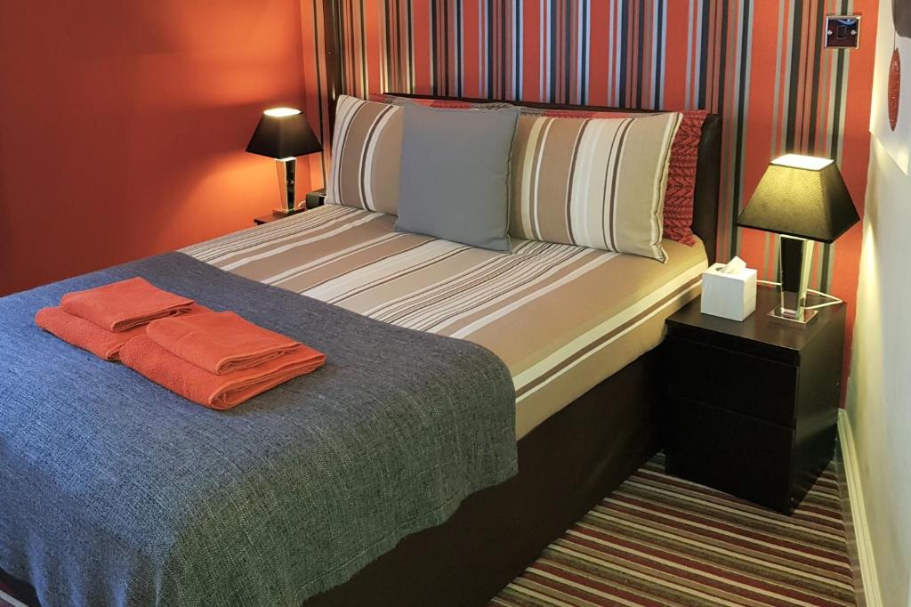 Robin 7 Lodge City Centre في نوتينغهام: غرفة نوم مع سرير مع منشفة برتقالية عليه