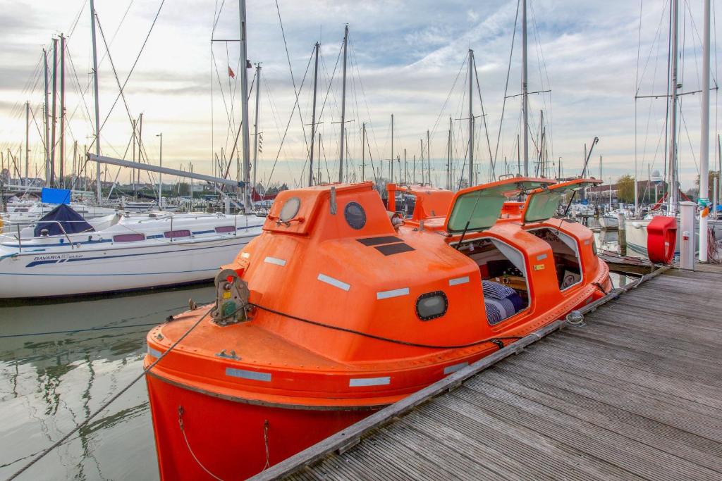 an orange boat parked next to a dock with boats at PolarStern - unique boatstay! in Monnickendam