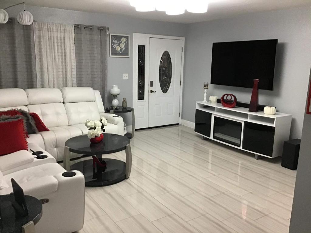 a living room with white furniture and a flat screen tv at Mary's Luxury House in Tampa