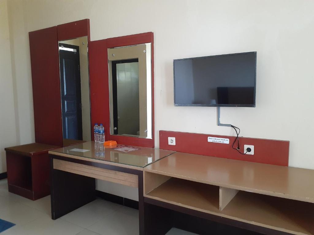a room with a desk and a tv on a wall at Surya Hotel & Resort in Baturaden