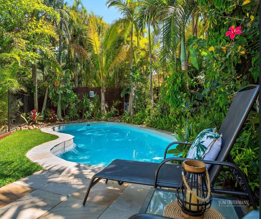 a bench next to a swimming pool with palm trees at Tropical Oasis in Marcus Beach