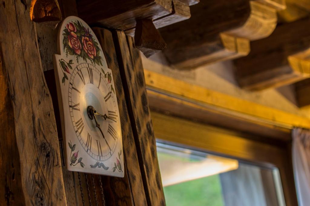 une horloge sur le côté d'un mur en bois dans l'établissement Digonera Historic Hotel B&B, à Rocca Pietore