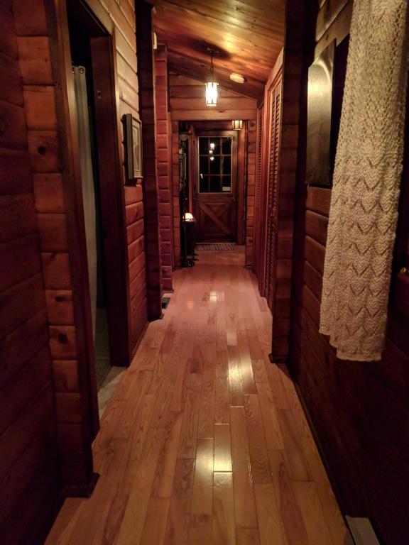 a long hallway with wooden floors and a door at Gîte le 308 Chambre bord de l'eau oka in Oka