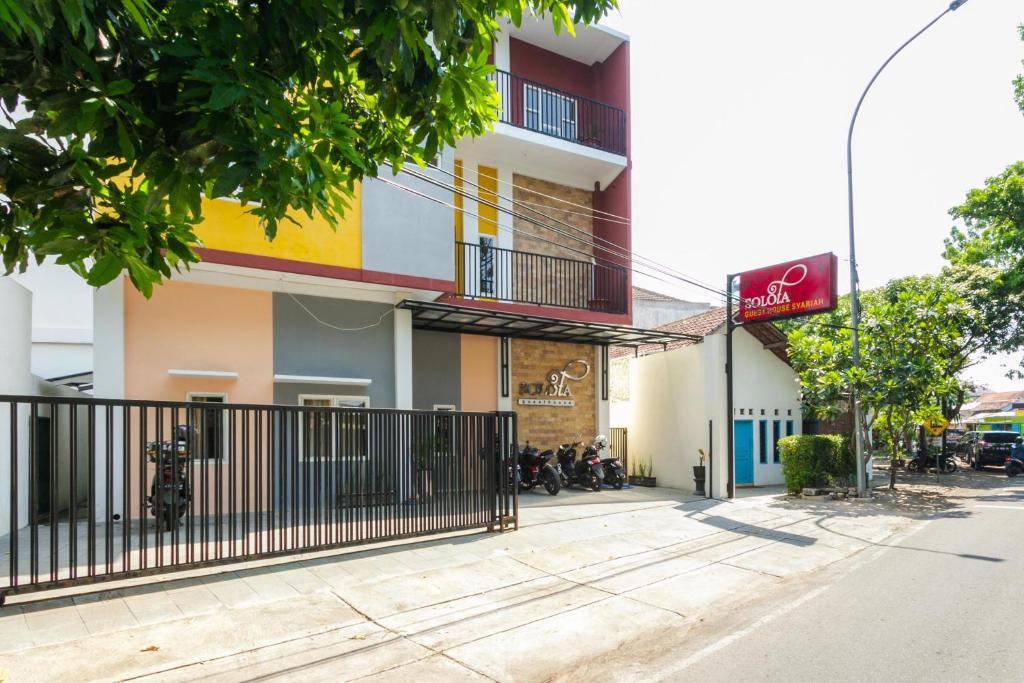 a building with a fence in front of a street at RedDoorz Syariah near Purwosari Train Station in Solo