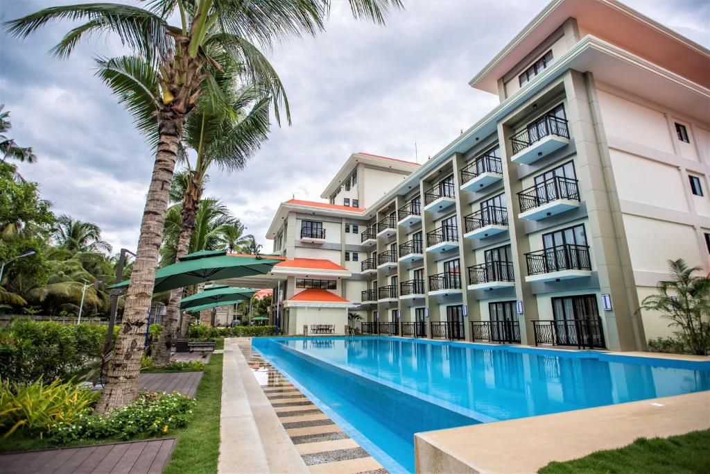 a hotel with a swimming pool in front of a building at Costa Palawan Resort in Puerto Princesa City