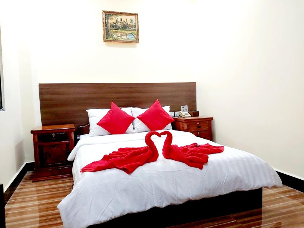 two red swans are sitting on a bed at Capitol One in Phnom Penh
