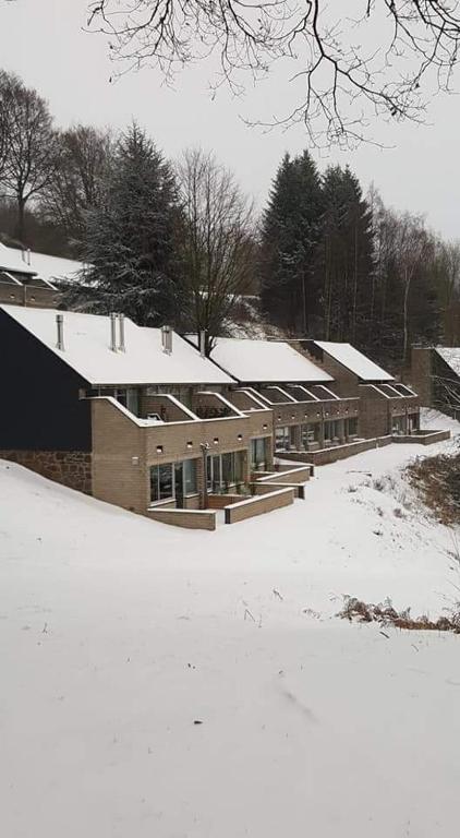 a building covered in snow in a snowy field at Les terrasses de Malmédy in Malmedy