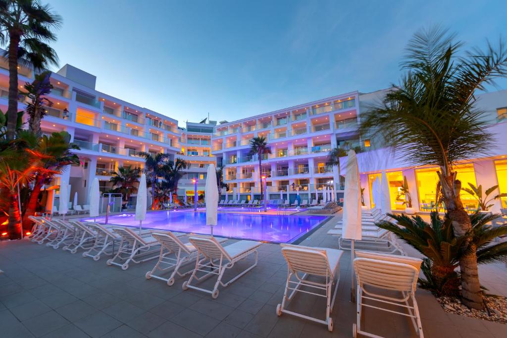 a hotel with chairs and a swimming pool at night at Limanaki Beach Hotel & Suites in Ayia Napa