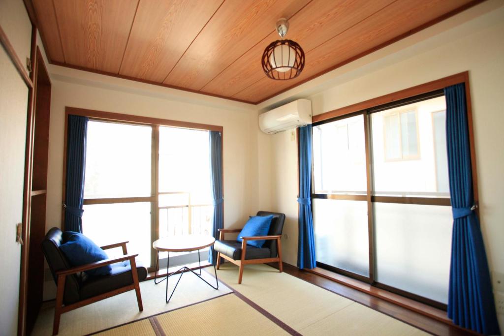 a room with two chairs and a table and windows at 一棟貸しの海宿 Kamakura SUN&BREEZE in Kamakura