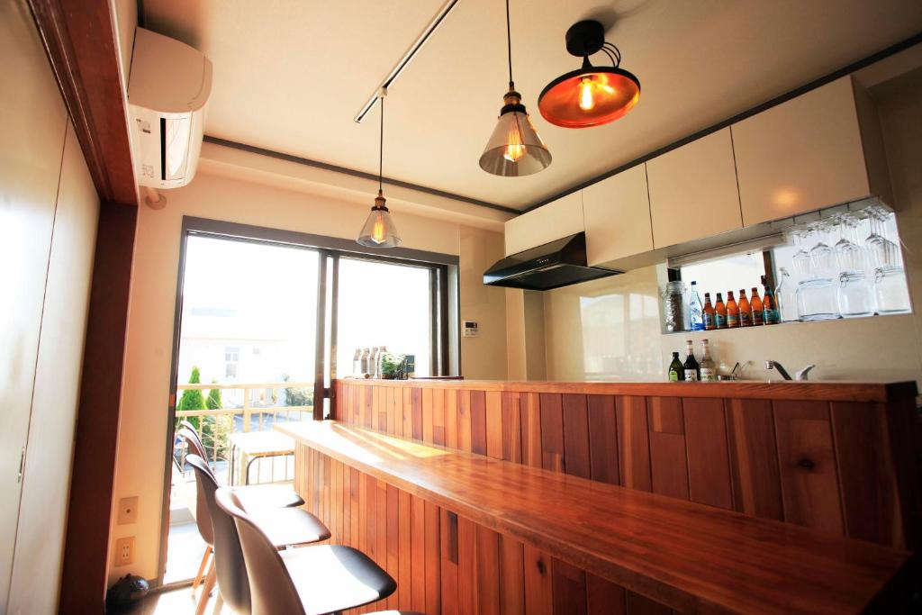 a kitchen with a bar with chairs and a window at 一棟貸しの海宿 Kamakura SUN&BREEZE in Kamakura