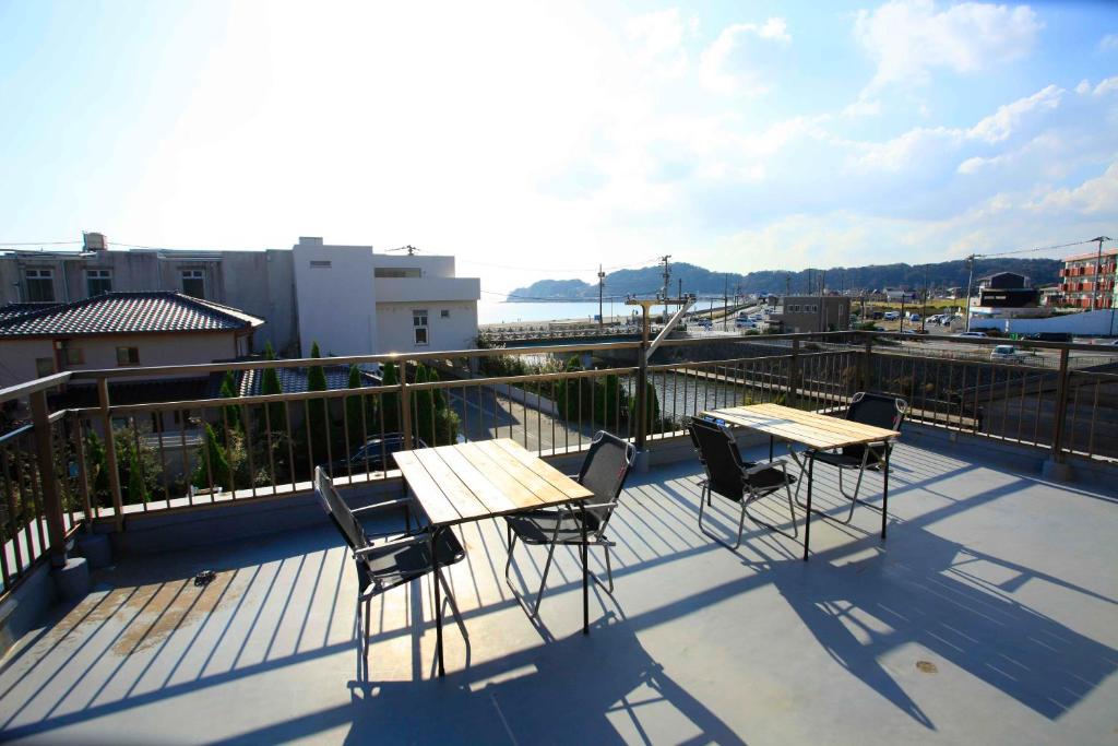 a patio with two tables and chairs on a balcony at 一棟貸しの海宿 Kamakura SUN&BREEZE in Kamakura