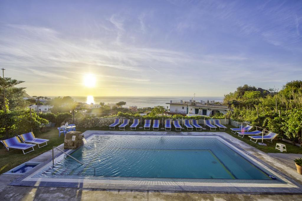 - une piscine avec des chaises longues et le coucher du soleil dans l'établissement Hotel Villa Cimmentorosso, à Ischia