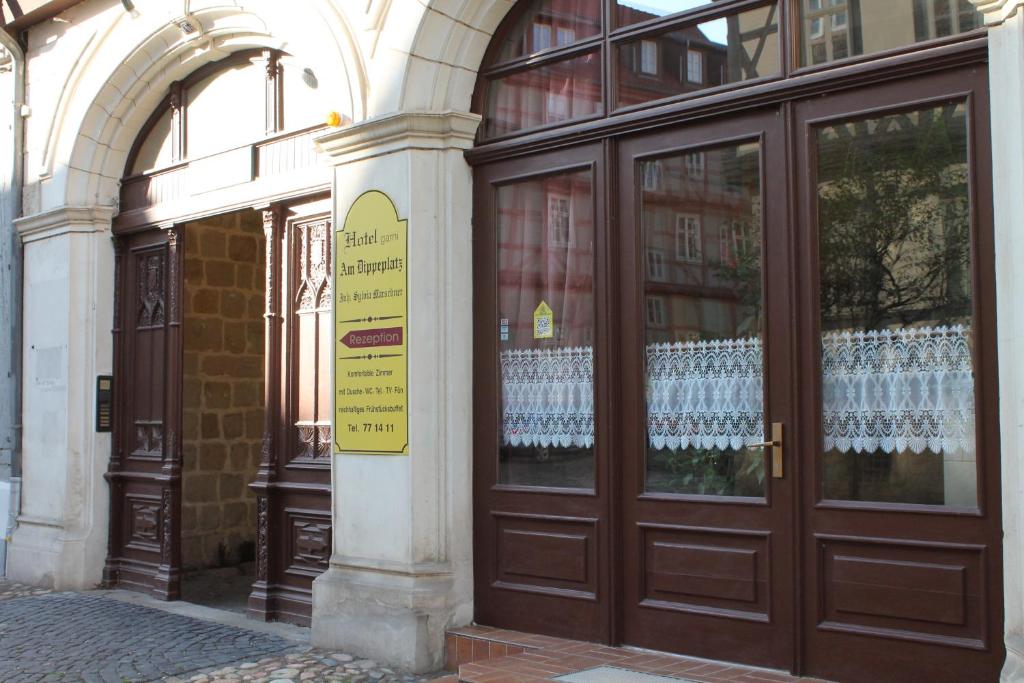 un bâtiment avec des portes brunes et un panneau sur lui dans l'établissement Hotel garni Am Dippeplatz, à Quedlinbourg