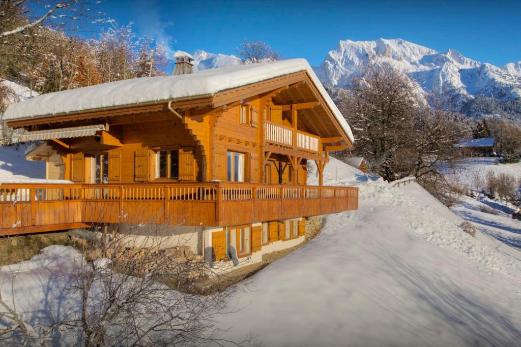 a large wooden house in the snow with mountains at Chalet Tekoa - OVO Network in Manigod