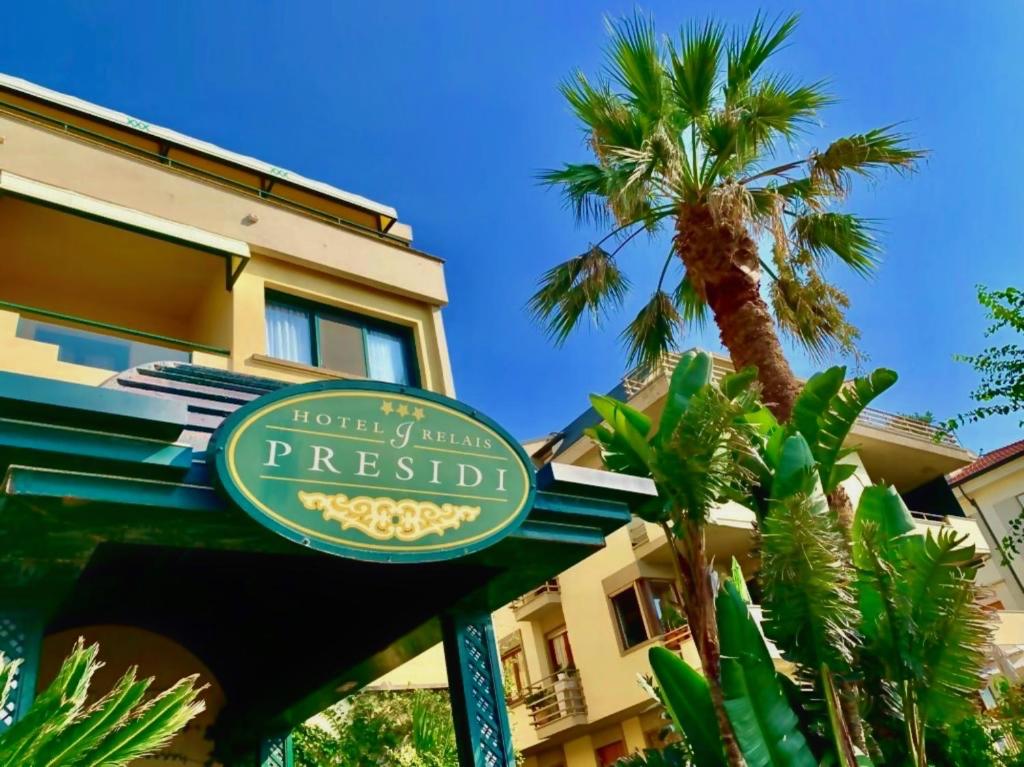 una señal de hotel frente a un edificio con una palmera en Hotel Relais I Presidi, en Orbetello