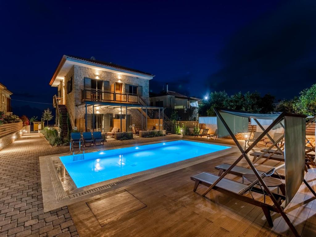 a swimming pool in front of a house at night at Sophia's Beach House in Levktron