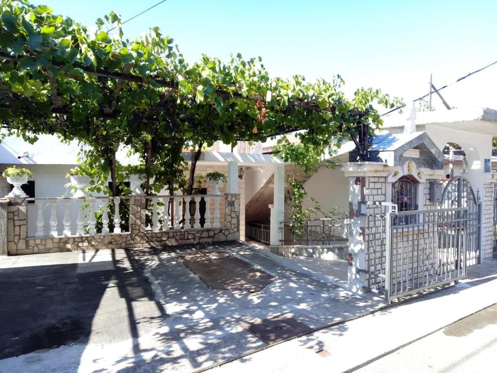 einen weißen Zaun mit einem Baum vor einem Haus in der Unterkunft Marijan apartments in Crikvenica