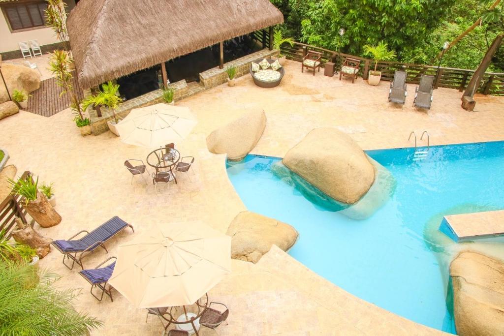 einen Blick über einen Pool mit Sonnenschirmen und Stühlen in der Unterkunft Casa Pedra Bonita in Rio de Janeiro